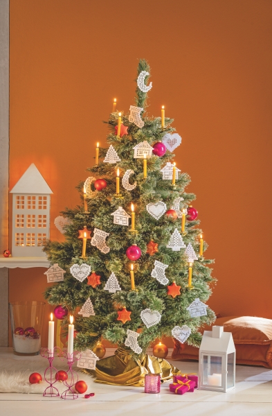 Weihnachtsbaum mit handgemachten Papierornamenten, rote Kugeln, gelbe Kerzen, DIY-Look.