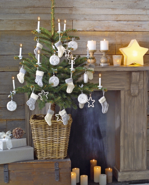 Kleine Socken und Sterne aus DIY-Strick zieren den Baum. Natürliche Farben und handgearbeitetes Design.