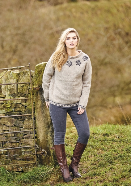 Beiger, selbstgemachtes Oberteil mit schwarzen Mustern, lange Ärmel, schmal geschnittene Jeans, braune Stiefel. Modisch.