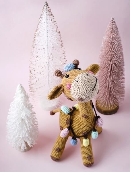 Bunte, handgemachte Häkelgiraffe mit Lichterkette; kreative Handarbeit, modisch im Boho-Stil.