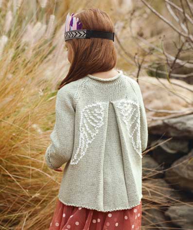 Beiger Strickpullover mit weißen Flügeln, Vintage-Stil, DIY, kombiniert mit gepunktetem Rock.