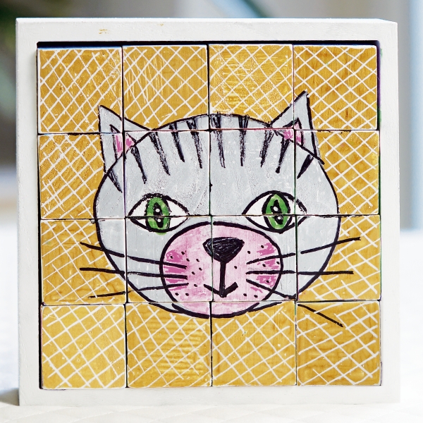 Handgemachtes Katzenmuster in Weiß, Rosa, Grün auf gelbem Gitterhintergrund. Kreativ, bunt, puzzleartig.