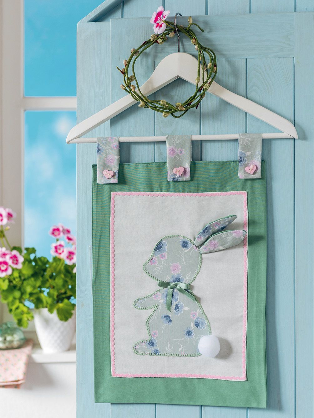 Selbstgemachte Wanddekoration mit floralem Hasenmotiv. Modische Pastelltöne, Stickerei, DIY-Charme.
