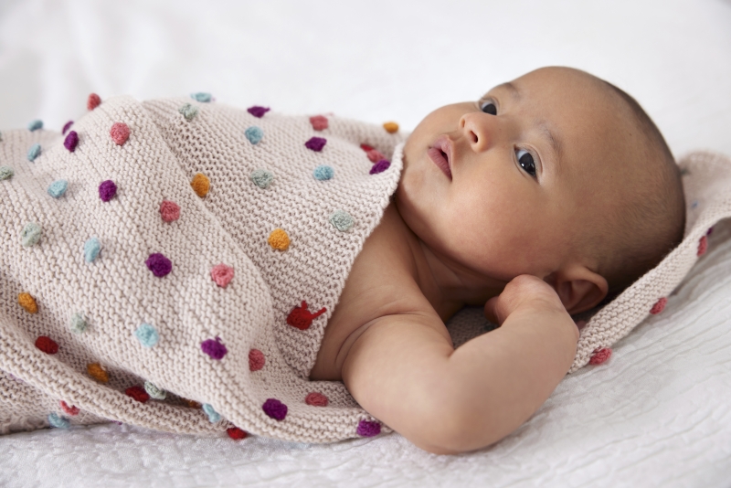 Handgestrickte Decke, hell mit bunten Punkten; modisch, einzigartig, DIY-Look.