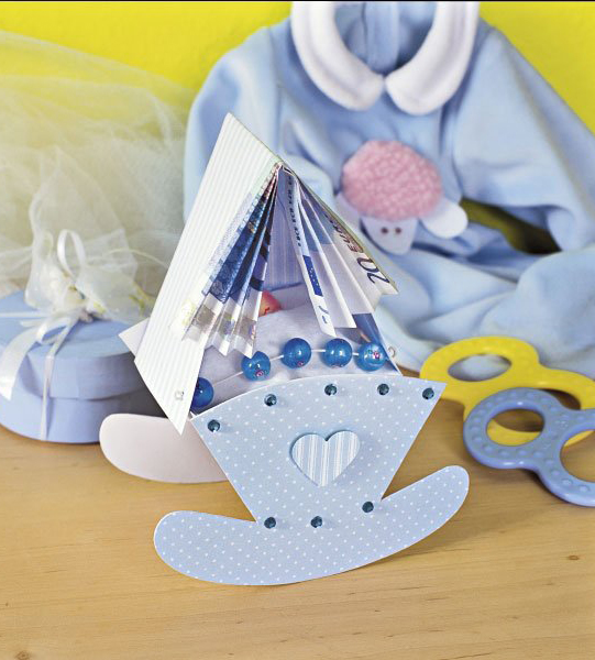 Handgemachtes, hellblaues Outfit mit weißen Akzenten, kariertes Babyspielzeug und selbstgemachte, verzierte Deko.