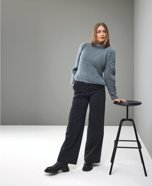 Modischer blauer Strickpullover, grobes Muster, kombiniert mit weiter, dunkler Hose. Zeitlos und stilvoll.