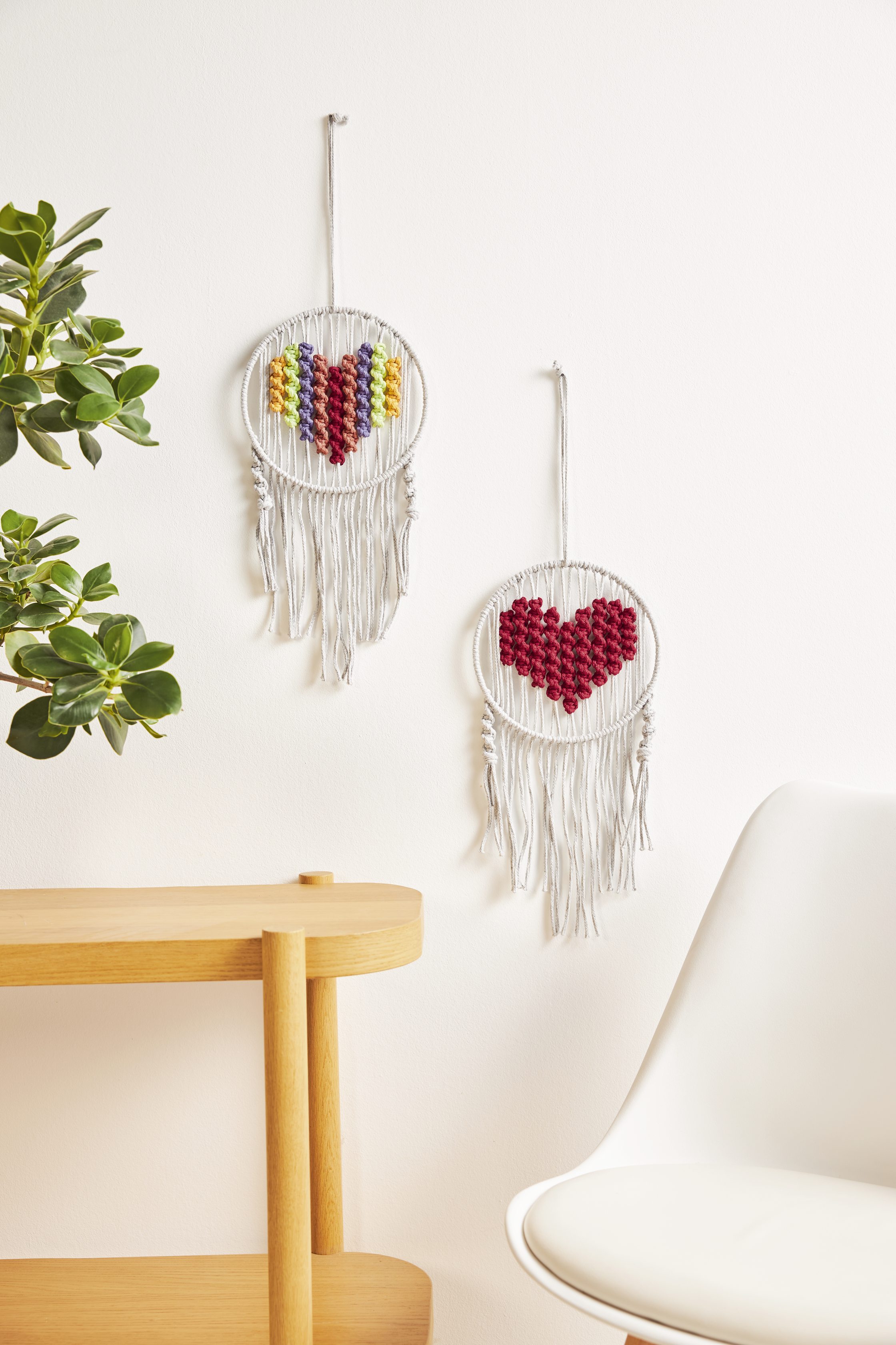 Selbstgemachte Wanddeko mit bunten Herzmotiven. Elegante Fransen, kreative Handarbeit, strahlende Farben.