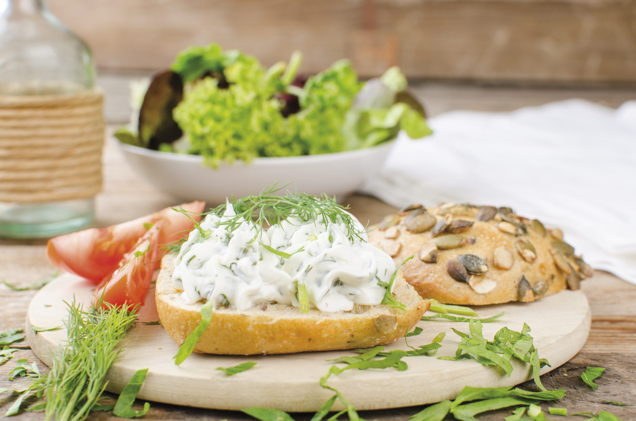 Rustikales Brötchen mit Frischkäse, bestreut mit frischem Dill, stilvoll serviert. DIY-Snack.