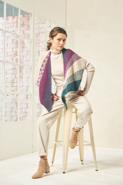 Bunter, handgemachter Schal mit geometrischen Mustern, kombiniert mit cremeweißem Rollkragenpullover und Hose.