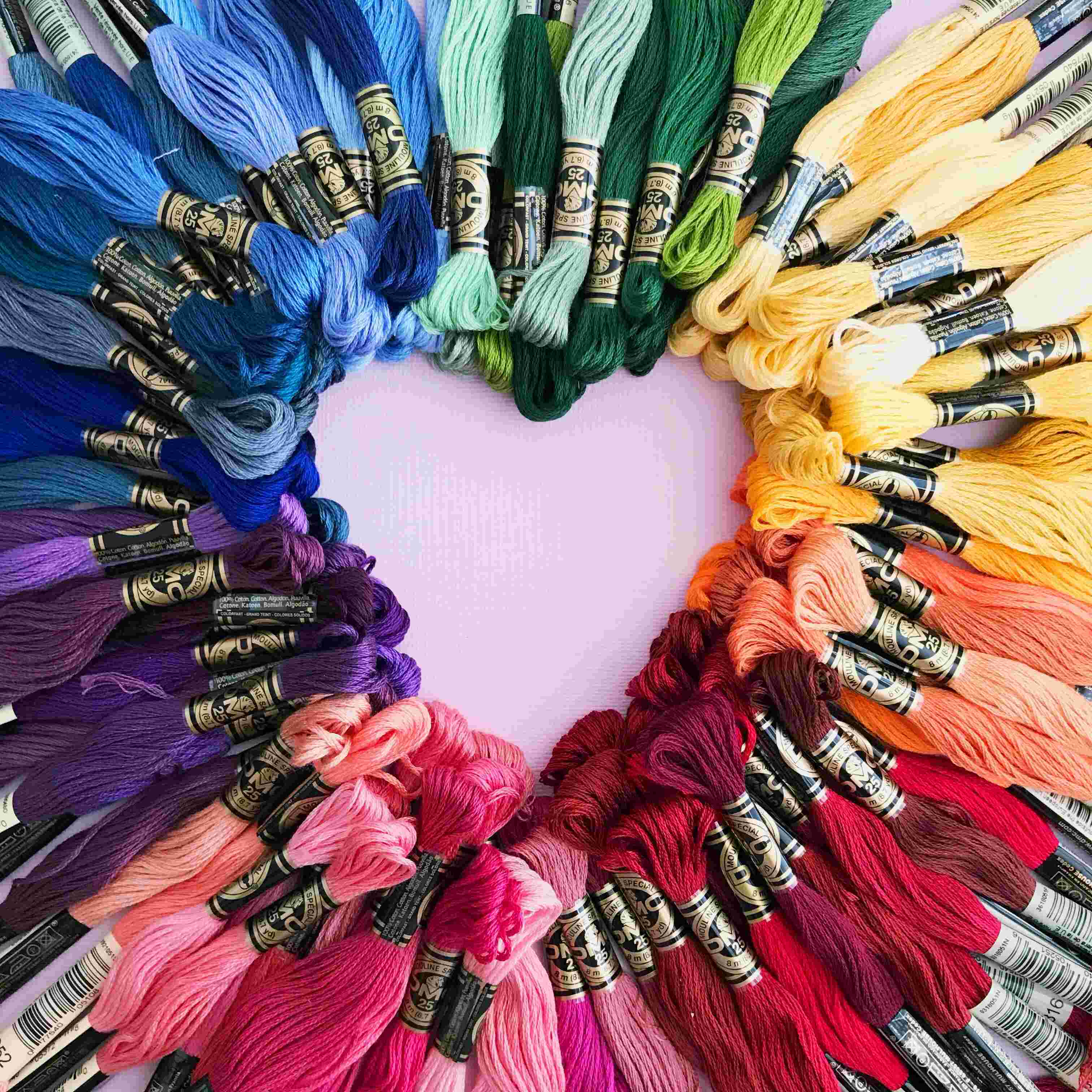 Stickgarne in Regenbogenfarben bilden ein Herz. Perfekt für DIY-Projekte in Handarbeit und kreative Designs.