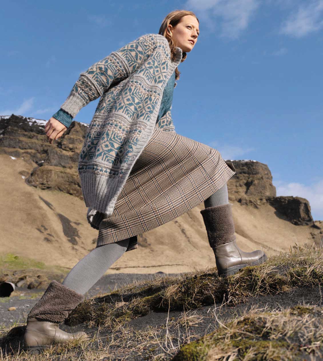 Modische Strickjacke in Blau-Grau mit geometrischem Muster, kariertes Kleid. Warme, bequeme Boots. DIY-Vintage-Look.