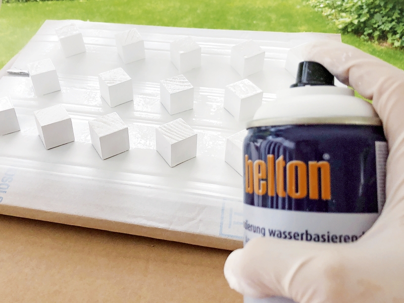 Weiße Würfel werden gleichmäßig mit Sprühfarbe bearbeitet. Handgemacht, kunstvoll, selbstgestaltet.