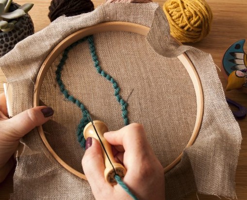 Modisch, handgemachte Stickerei mit türkisfarbenem Garn auf beigem Stoff. DIY-Kunst mit rustikalem Charme.