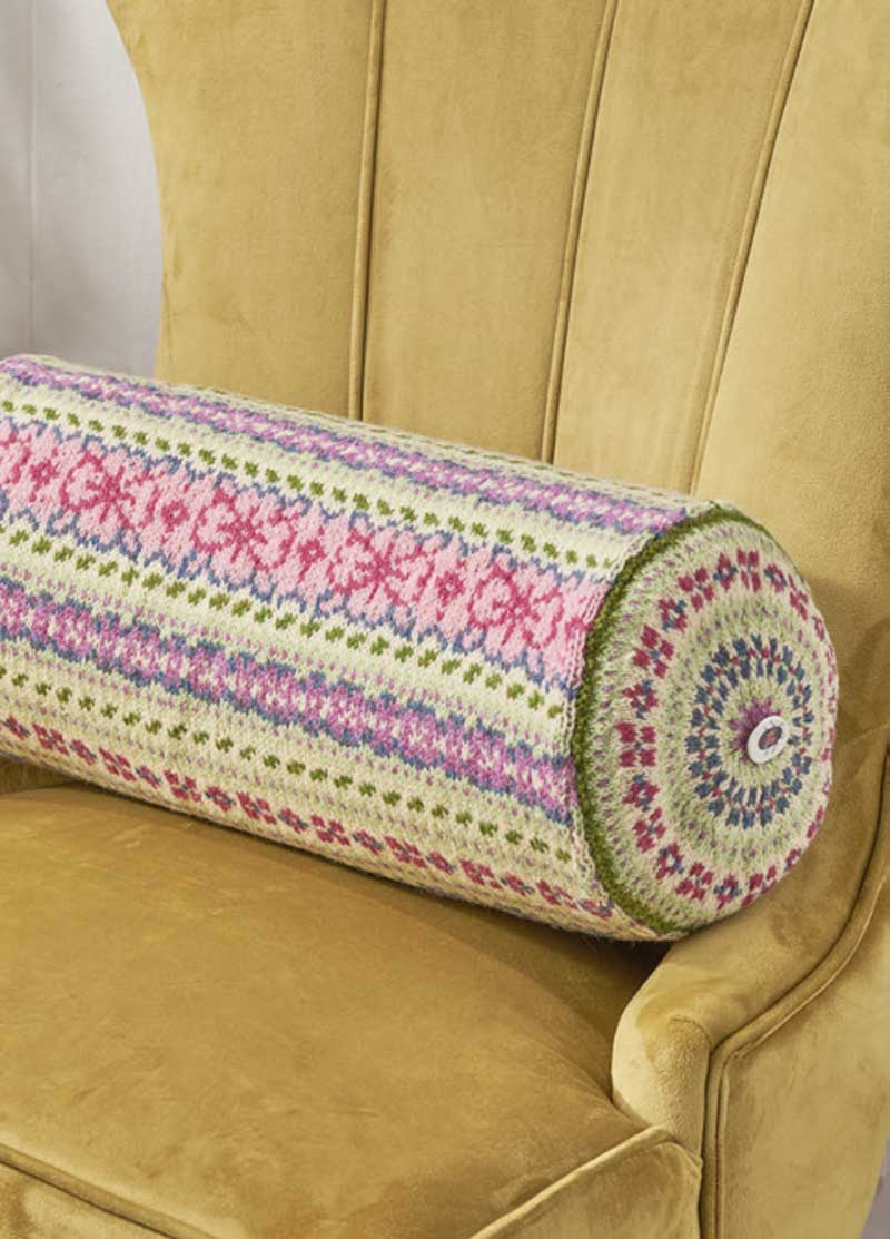 Zylinderkissen mit floralen Mustern in Rosa, Grün und Lila. Kunstvoll gestrickt, DIY-Charme.