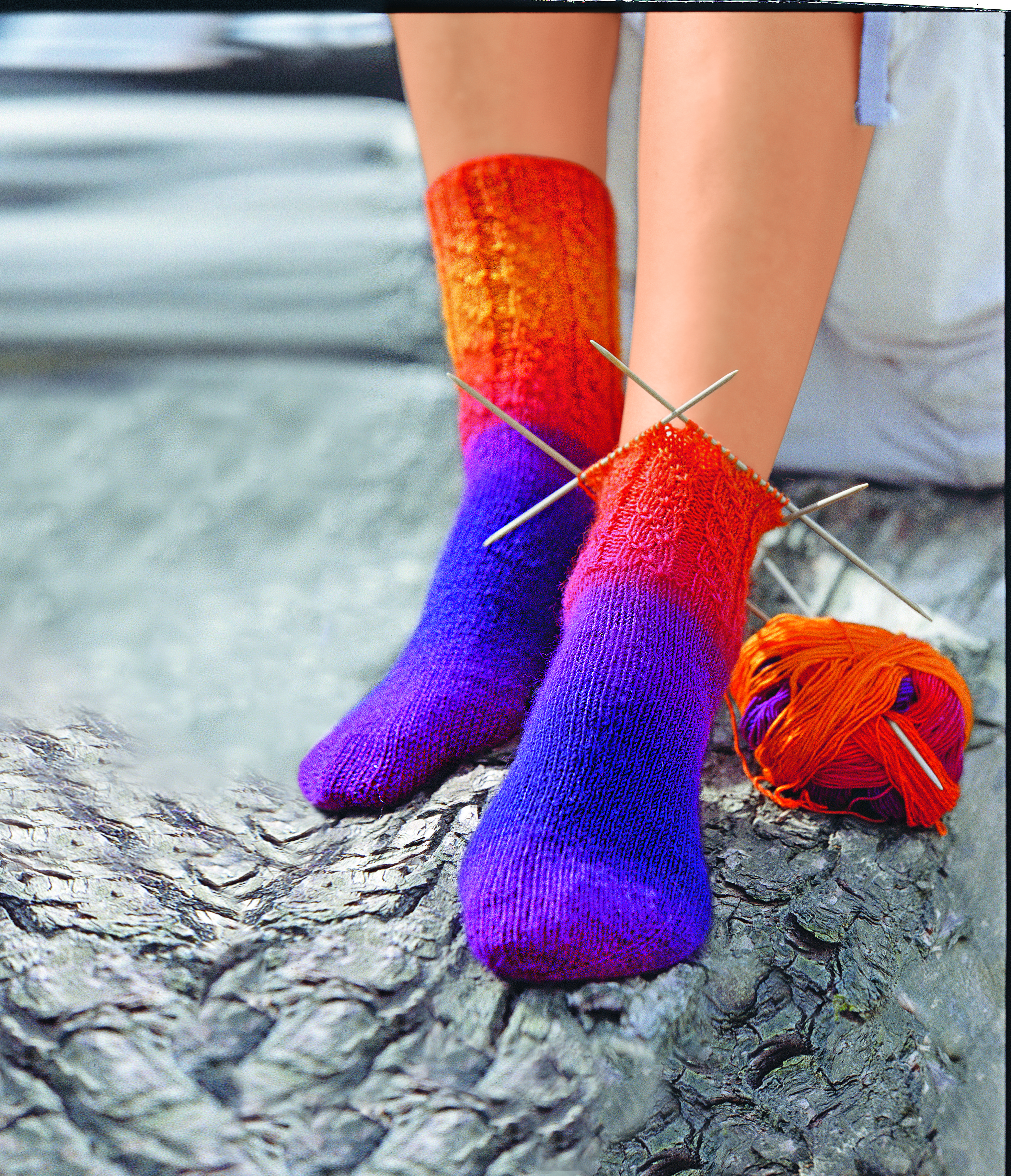 Selbstgemachte Socken in lebhaftem Rot-Orange-Lila-Verlauf. DIY, handgestrickt, warmes Farbspiel.