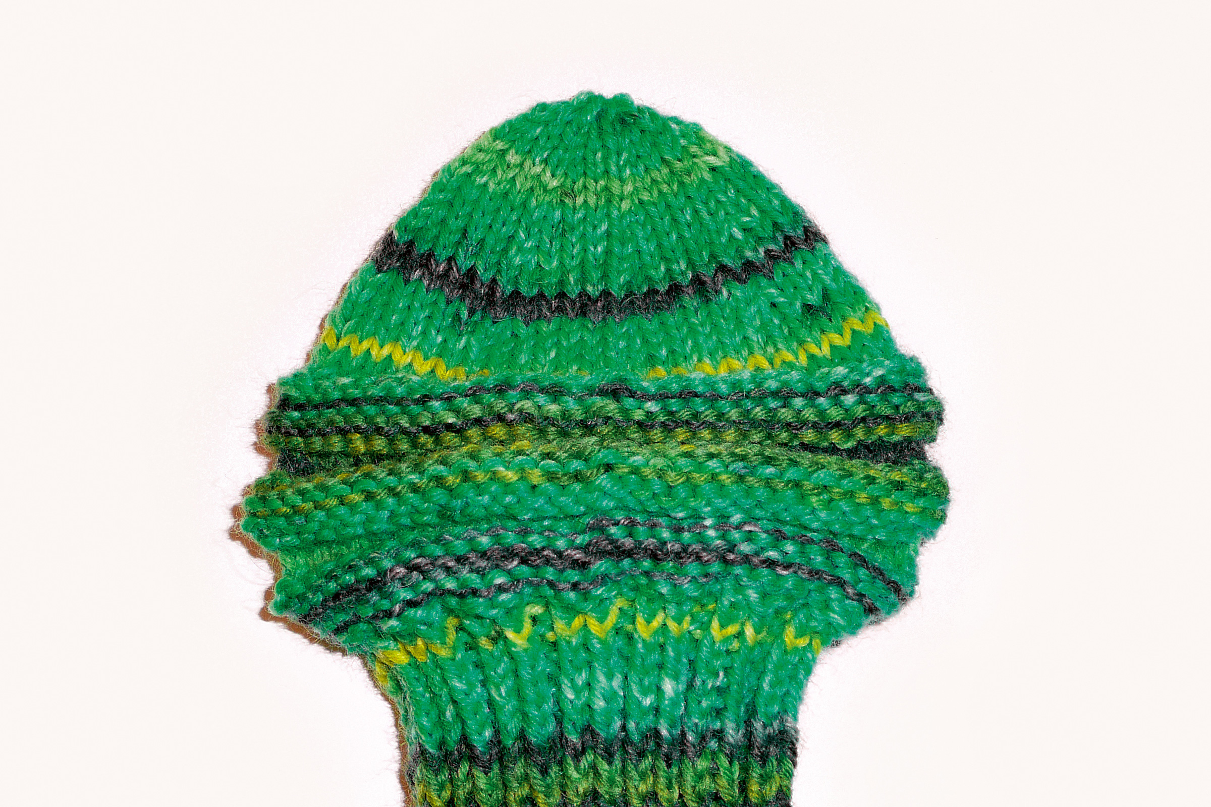Grüne handgemachte Strickmütze mit gelben und schwarzen Streifen. Modisches DIY-Accessoire.