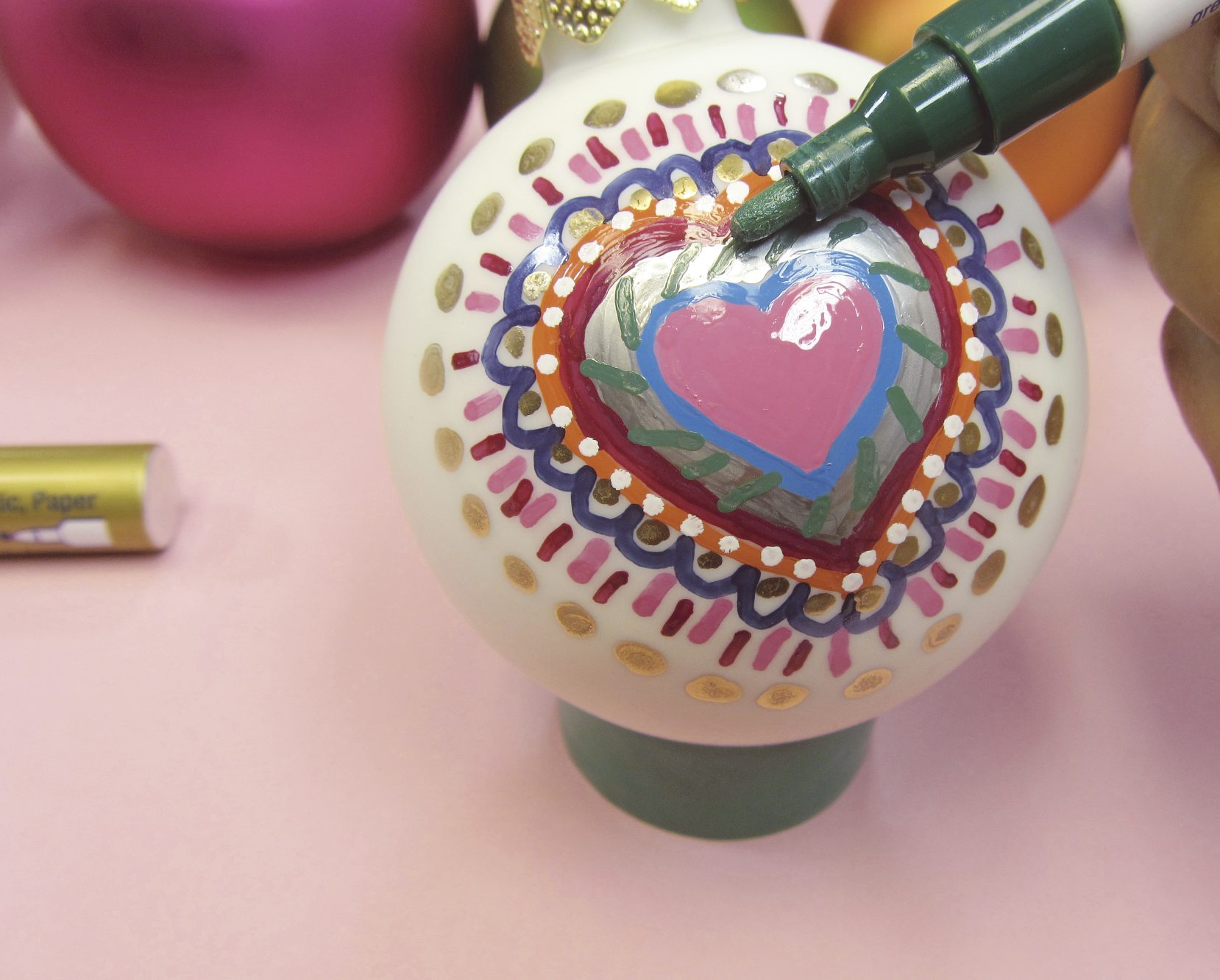 Bunte Herzmuster auf Kugel, DIY-Stil, lebendige Farben, kreative Handarbeit, kunstvoll verziert.