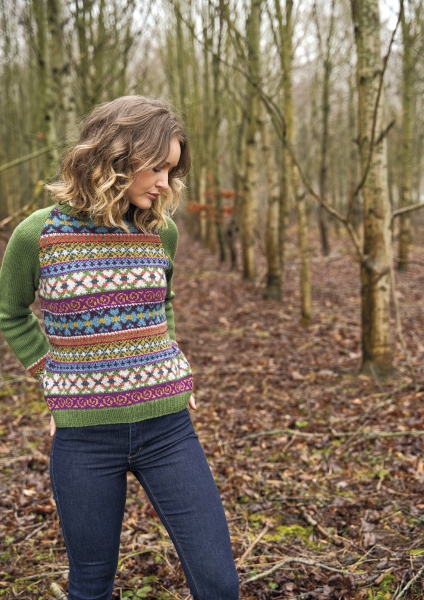 Bunter, gemusterter Pullover im DIY-Stil mit grünen Ärmeln, kombiniert mit modischen, dunklen Jeans.