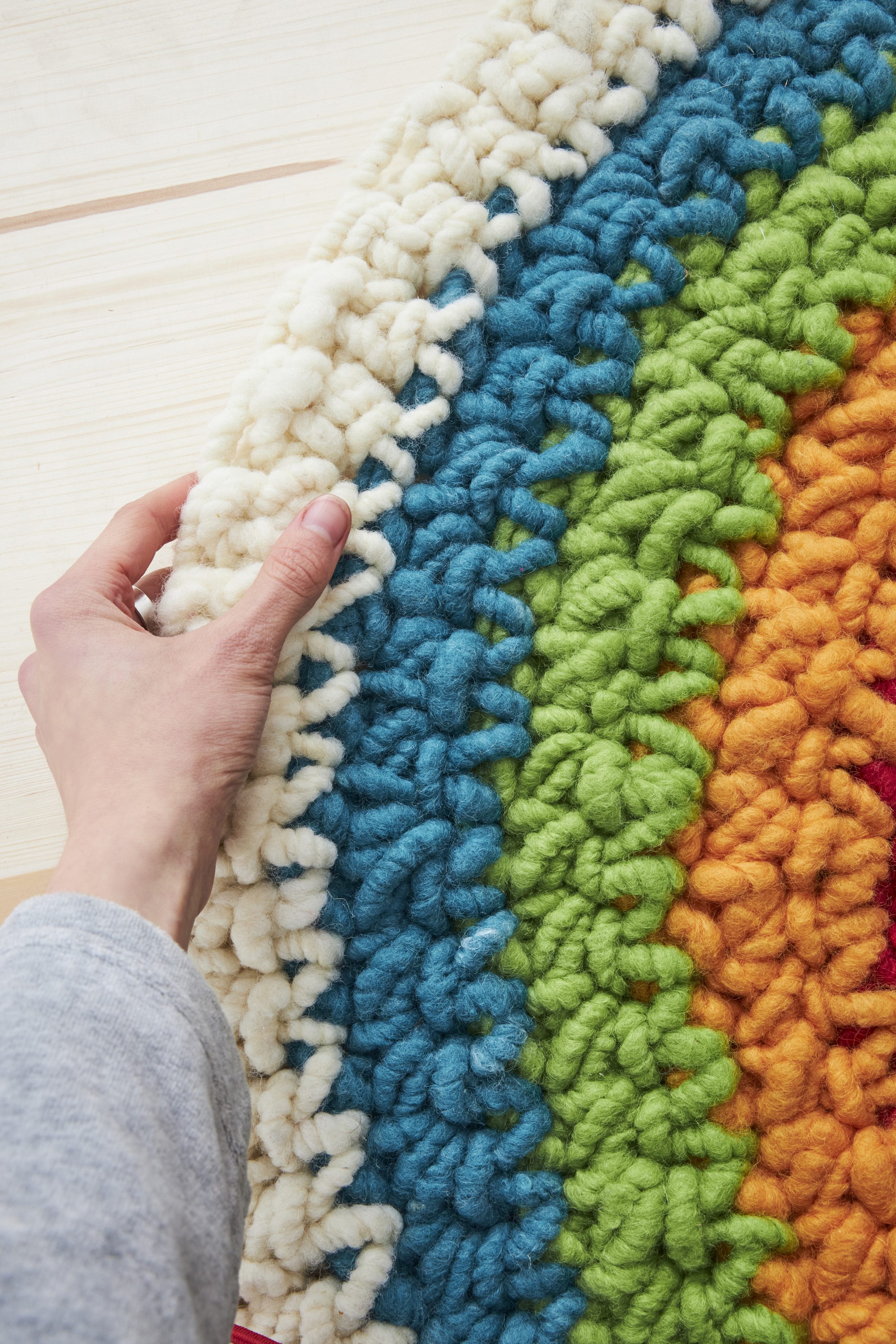 Häkelteppich in kräftigen Farben: Blau, Grün, Orange. Grobes Muster, handgemacht, DIY.
