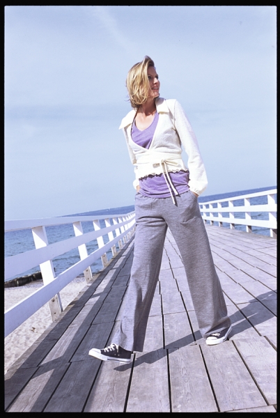 Graue weite Hose, lila Top, cremefarbene Jacke. Modische, legere, sportliche Kleidung.