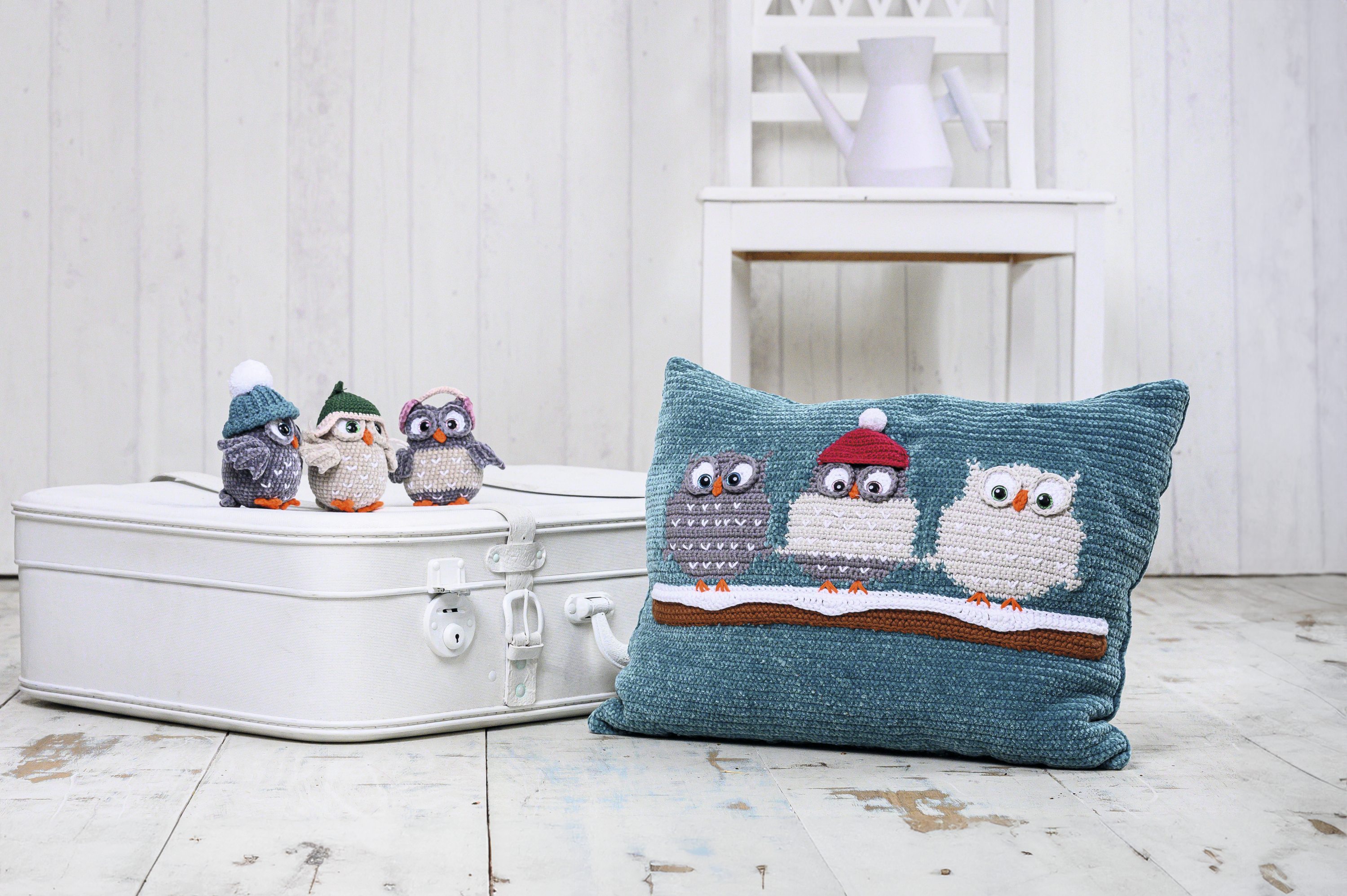 Handgemachte Eulenmotive auf Kissen und Figuren, in Blau und Erdtönen, modisches DIY mit winterlichem Flair.