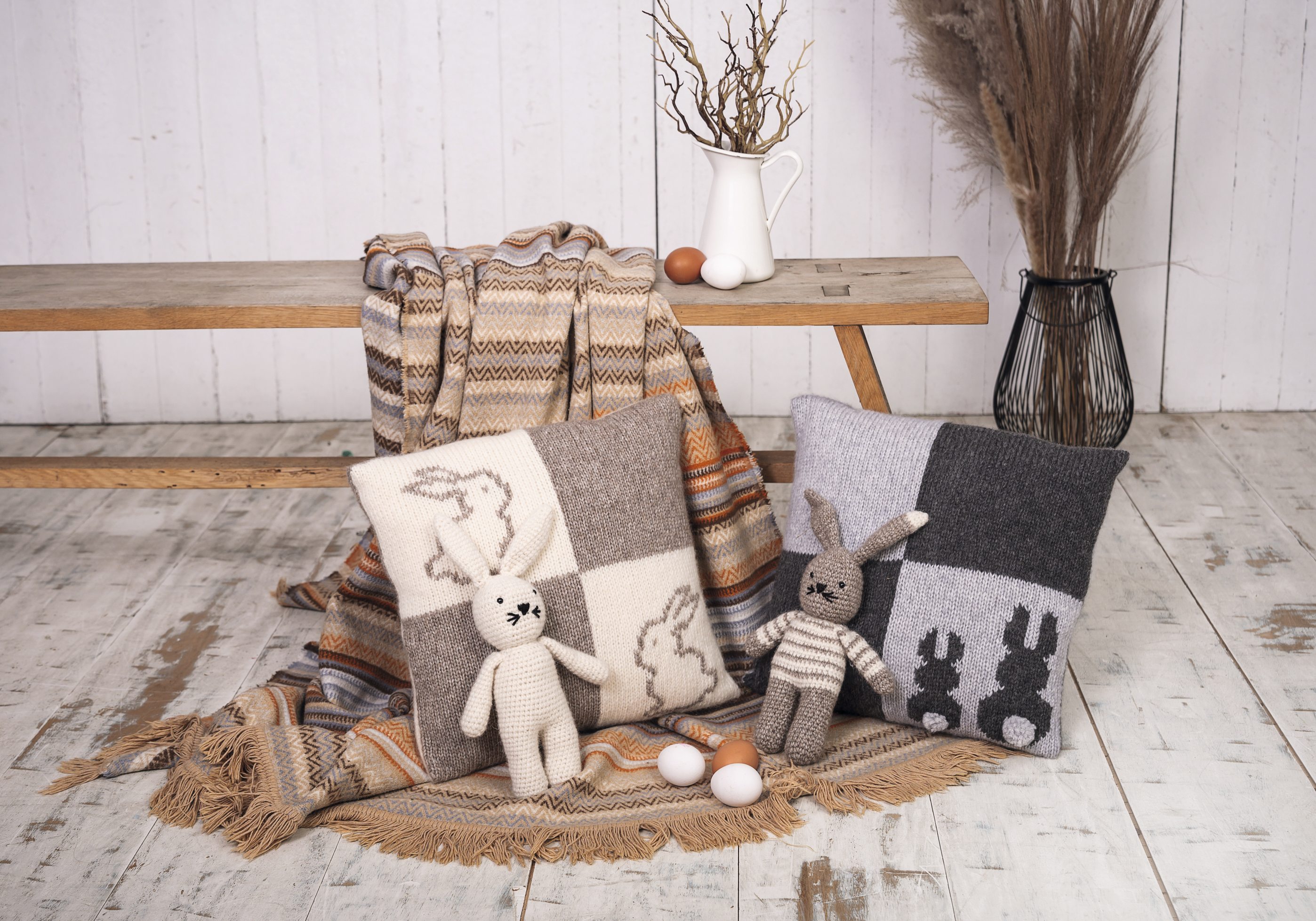 Handgemachte Kissen mit Hasenmotiv, neutrale Erdtöne, gestrickte Details; harmonisch, modisch, DIY-Flair.