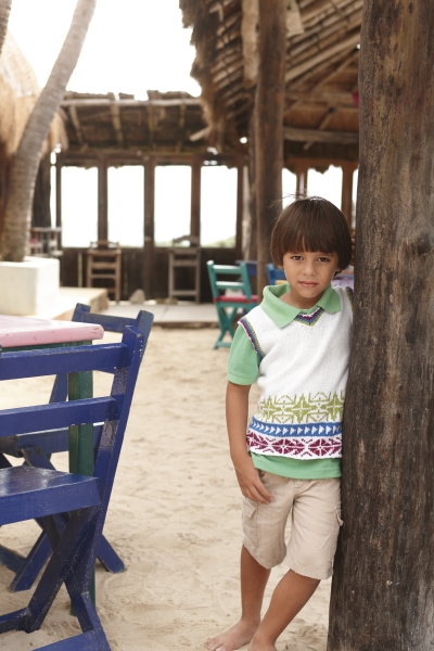 Poloshirt mit grünem Kragen, bunten Mustern, beige Shorts; modischer, lebendiger Stil.