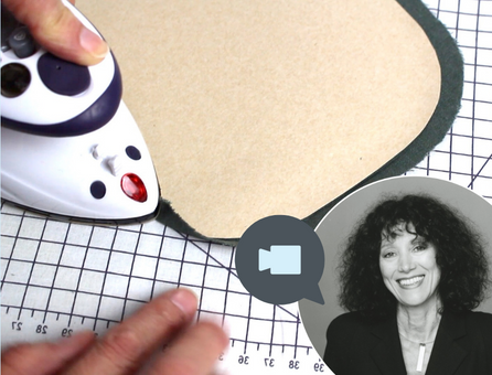 Modisch und handgemacht: Bügeleisen formt Stoffkanten auf kariertem Untergrund für präzises Nähen.