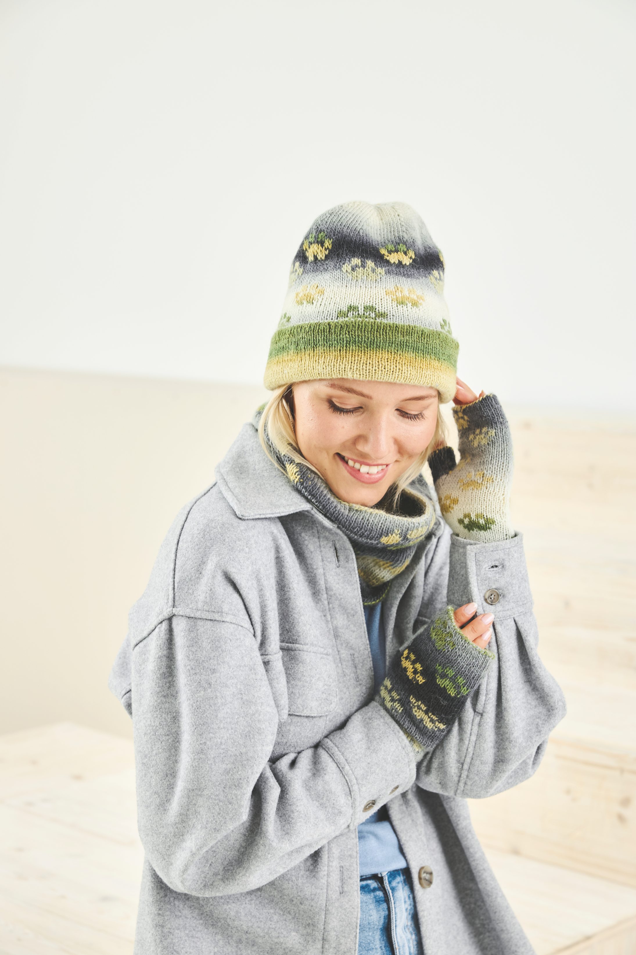 Bunte Mütze & Handschuhe im DIY-Stil. Graues Oversize-Hemd, kreativ gestrickt, mit natürlicher Farbpalette.