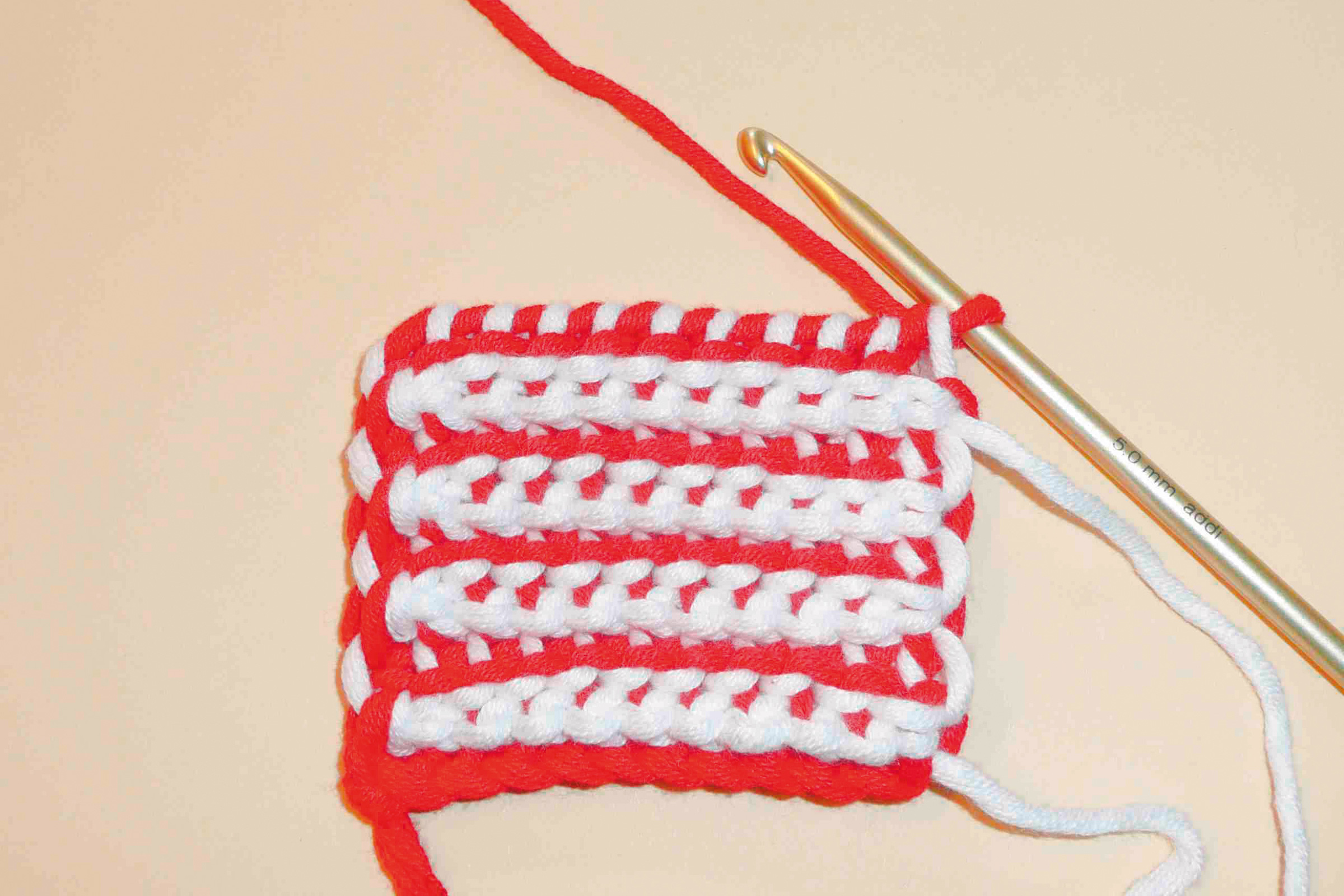 Handgemachtes Häkeldesign in Rot-Weiß, zweifarbig gestreift. DIY-Look, robustes, kreatives Muster.