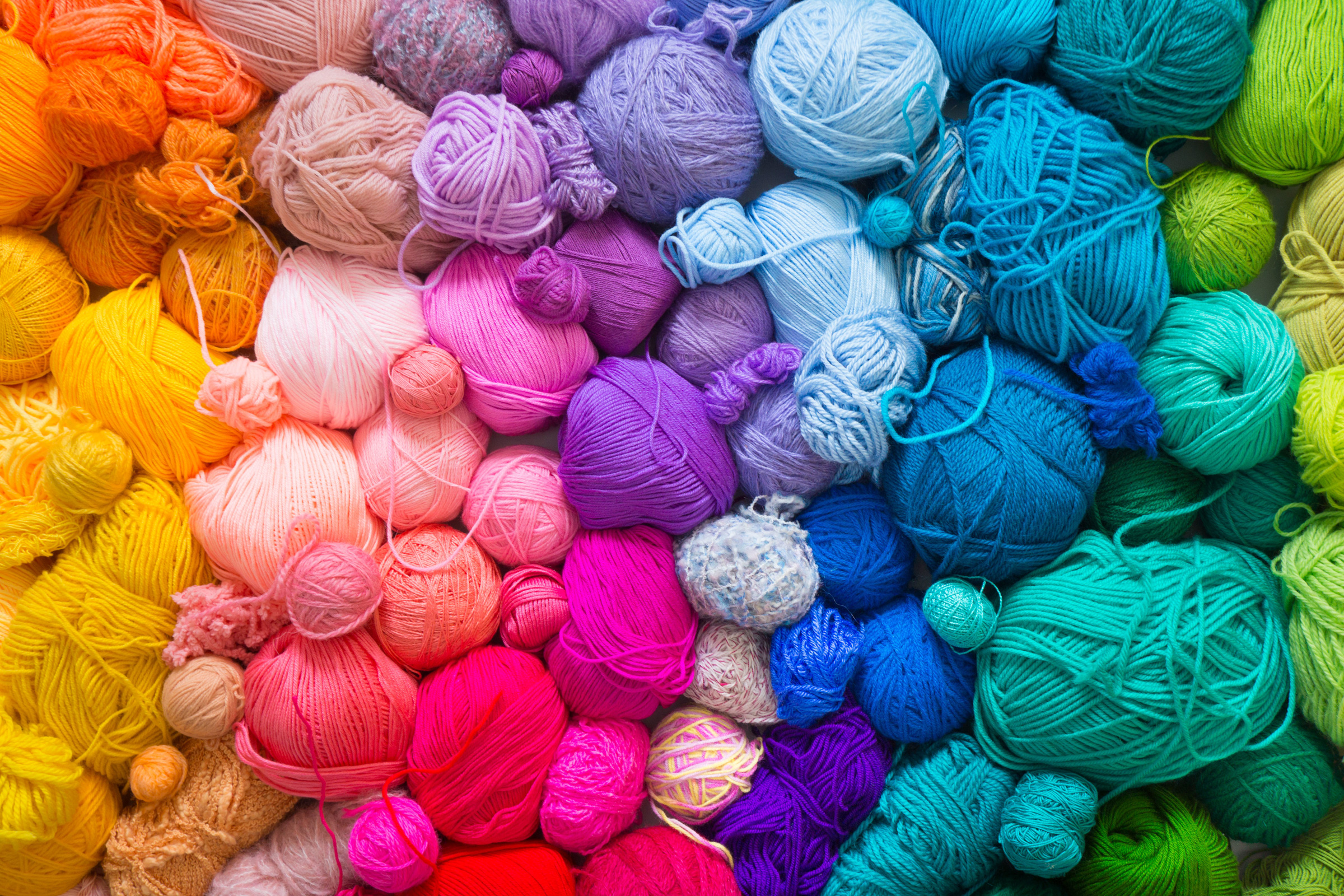 Vielzahl farbenfroher Wollknäuel. Ideal für handgemachte und DIY-Projekte. Strahlende Regenbogenpalette.