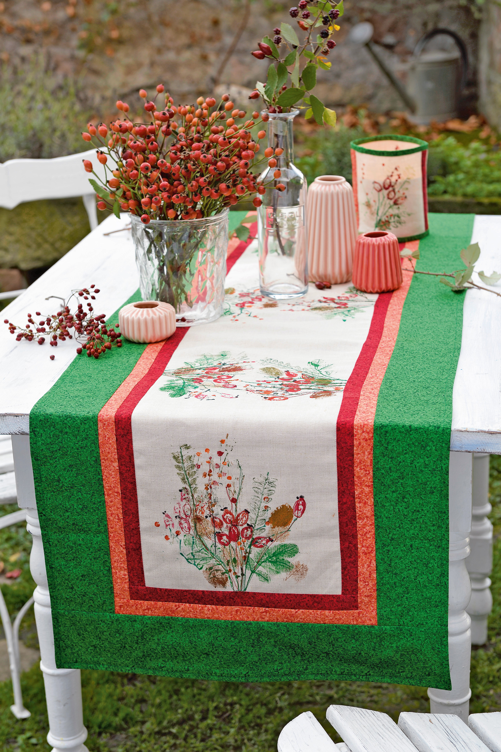 Grüner Tischläufer mit roter Bordüre, florale Motive, handgemacht, DIY-Dekoration, saisonale Farbgestaltung.