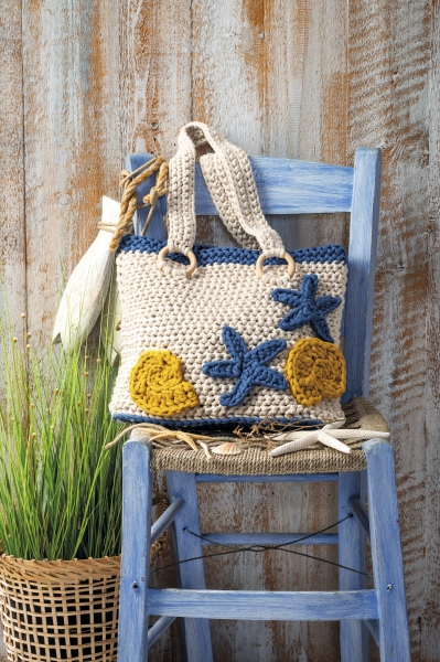 Handgemachte, beige-gelbe Tasche mit blauen Sternform-Akzenten, gehäkeltes Muster, DIY-Stil.