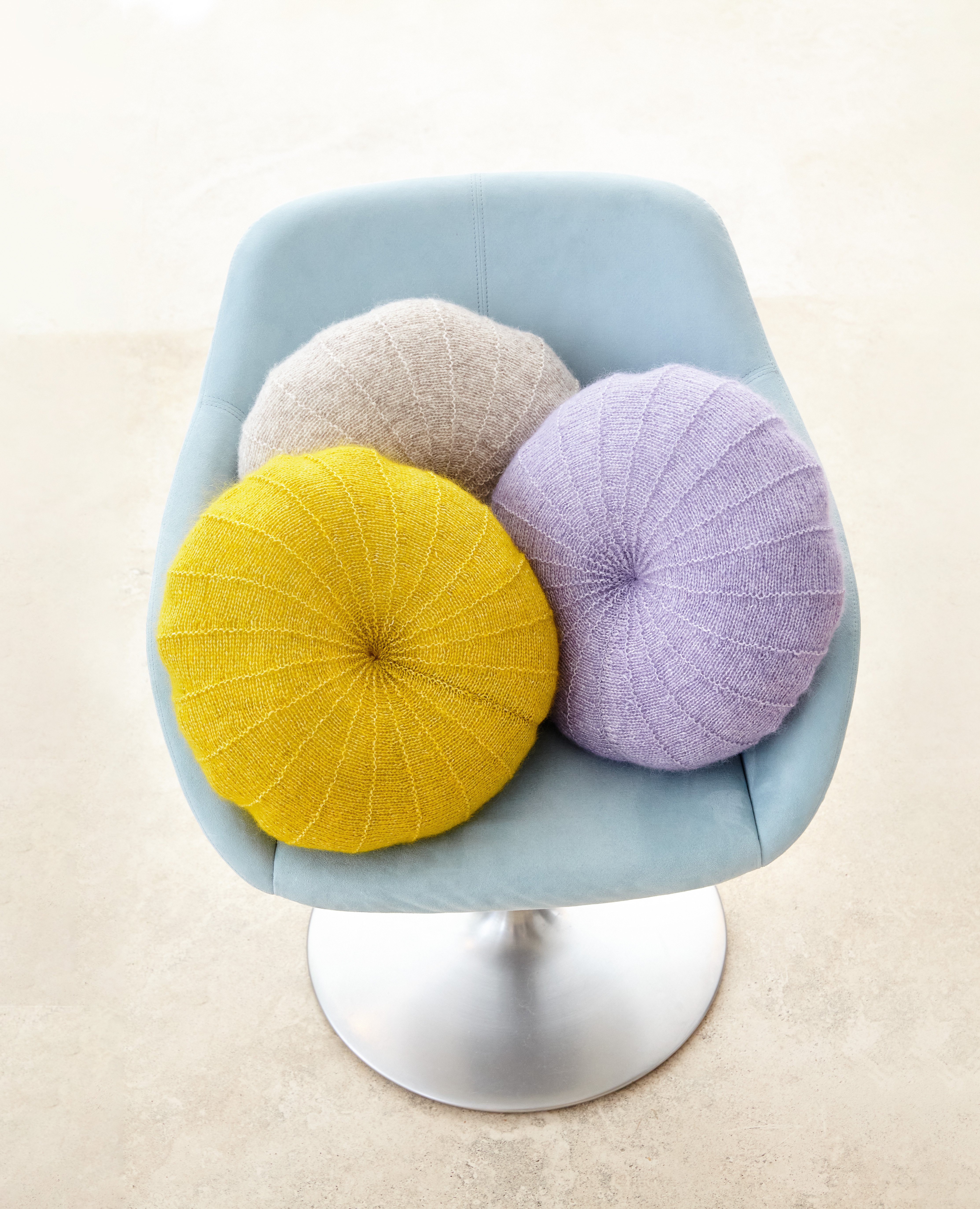 Drei runde Kissen in Pastellgelb, Lila, Grau; gestrickte Textur; modern, handgemacht.