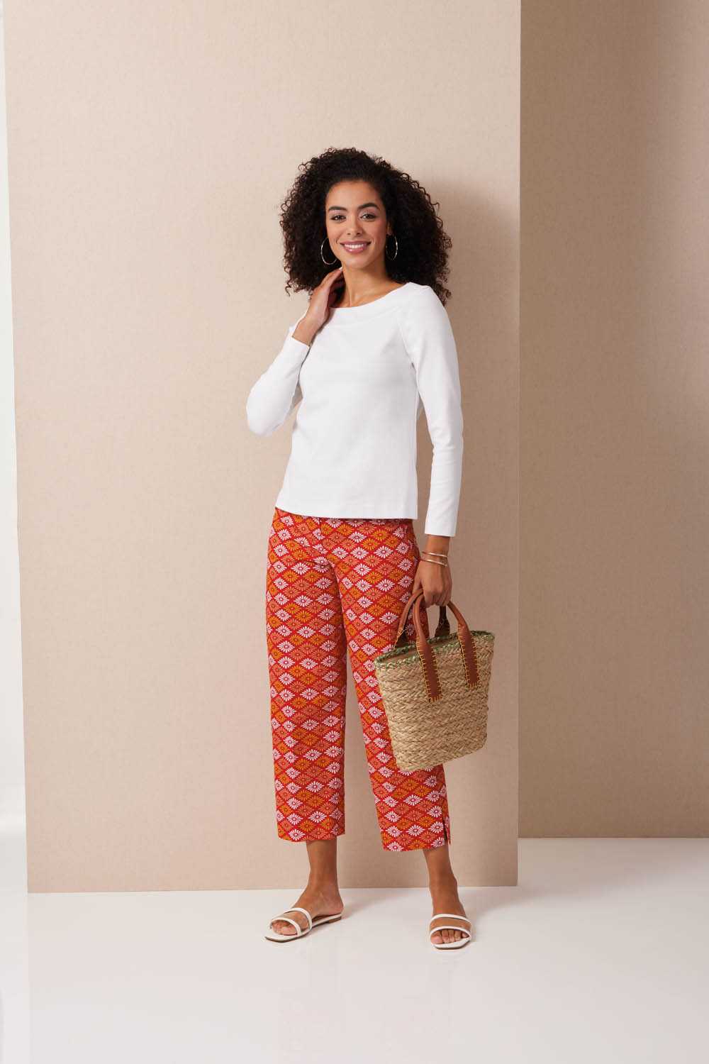 Moderne rote Print-Hose, weißes Oberteil, handgemachte Strohtasche. Lässiger, sommerlicher Stil.