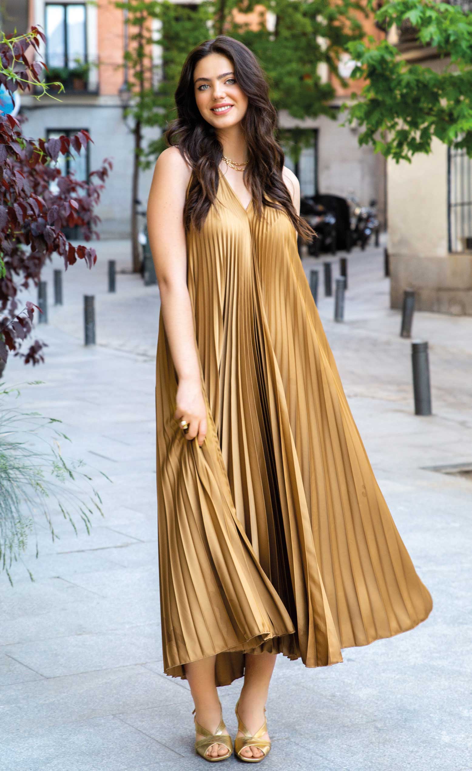 Elegantes, goldenes Kleid mit fließenden Plisseefalten. Ärmelloser Schnitt, modisch und stilvoll.