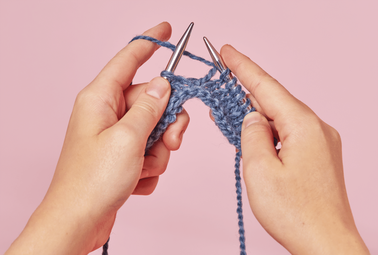 Hände, die mit Rundstricknadel stricken
