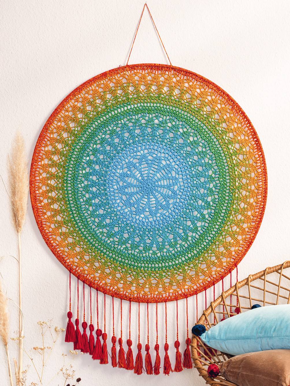 Modisch, handgearbeitetes Mandala-Wanddekor in Regenbogenfarben mit feinen Mustern und roten Quasten.