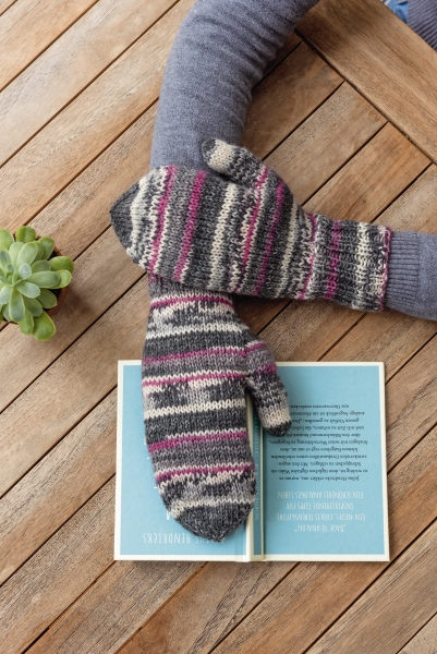 Modische handgestrickte Fäustlinge mit buntem Streifenmuster in Grau, Rosa und Beige. Diy-Handarbeit.