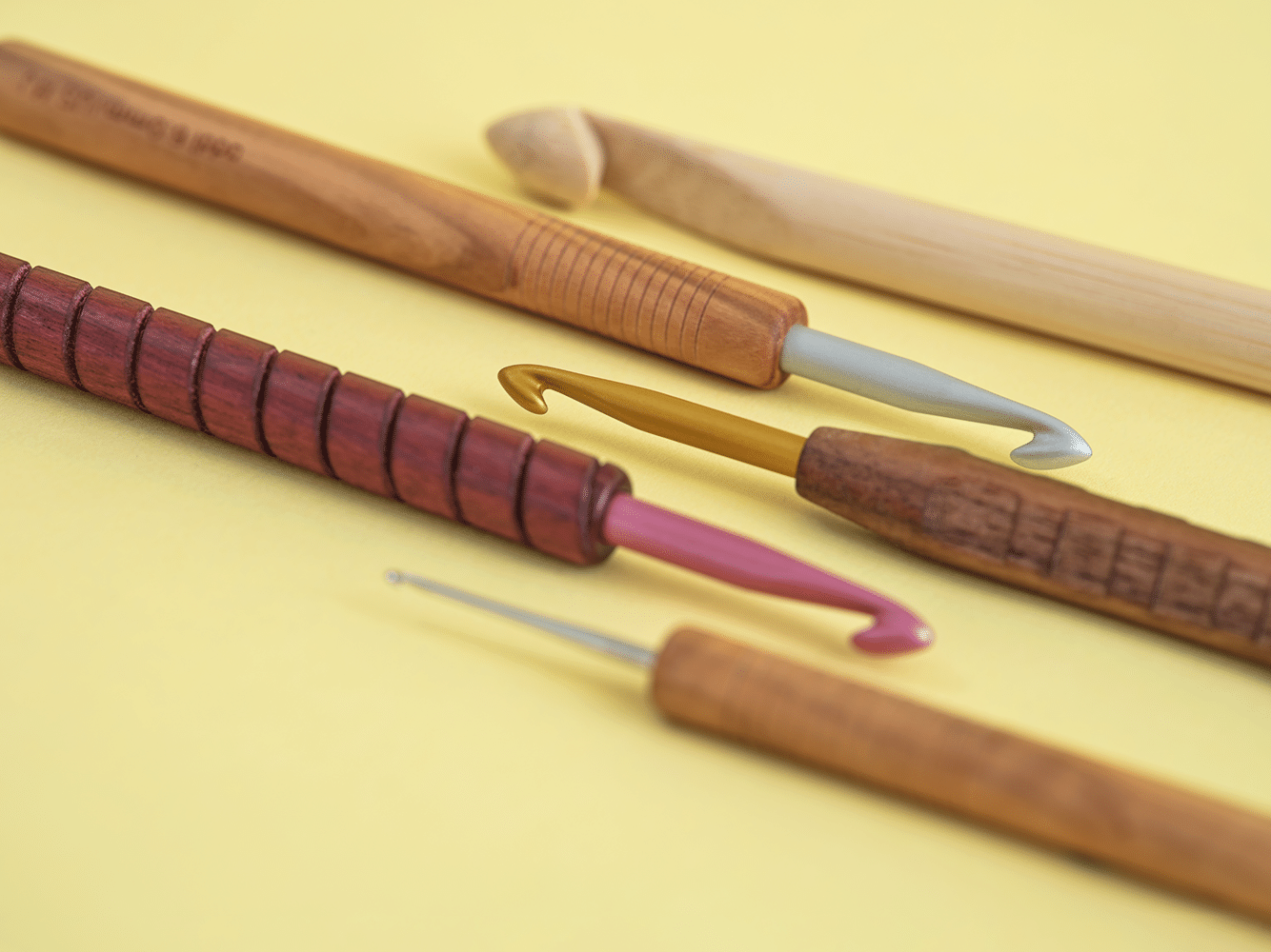 Bunte, handgemachte Häkelnadeln in Holz und Metall, DIY-Stil. Vielfältige Muster und ergonomische Designs.