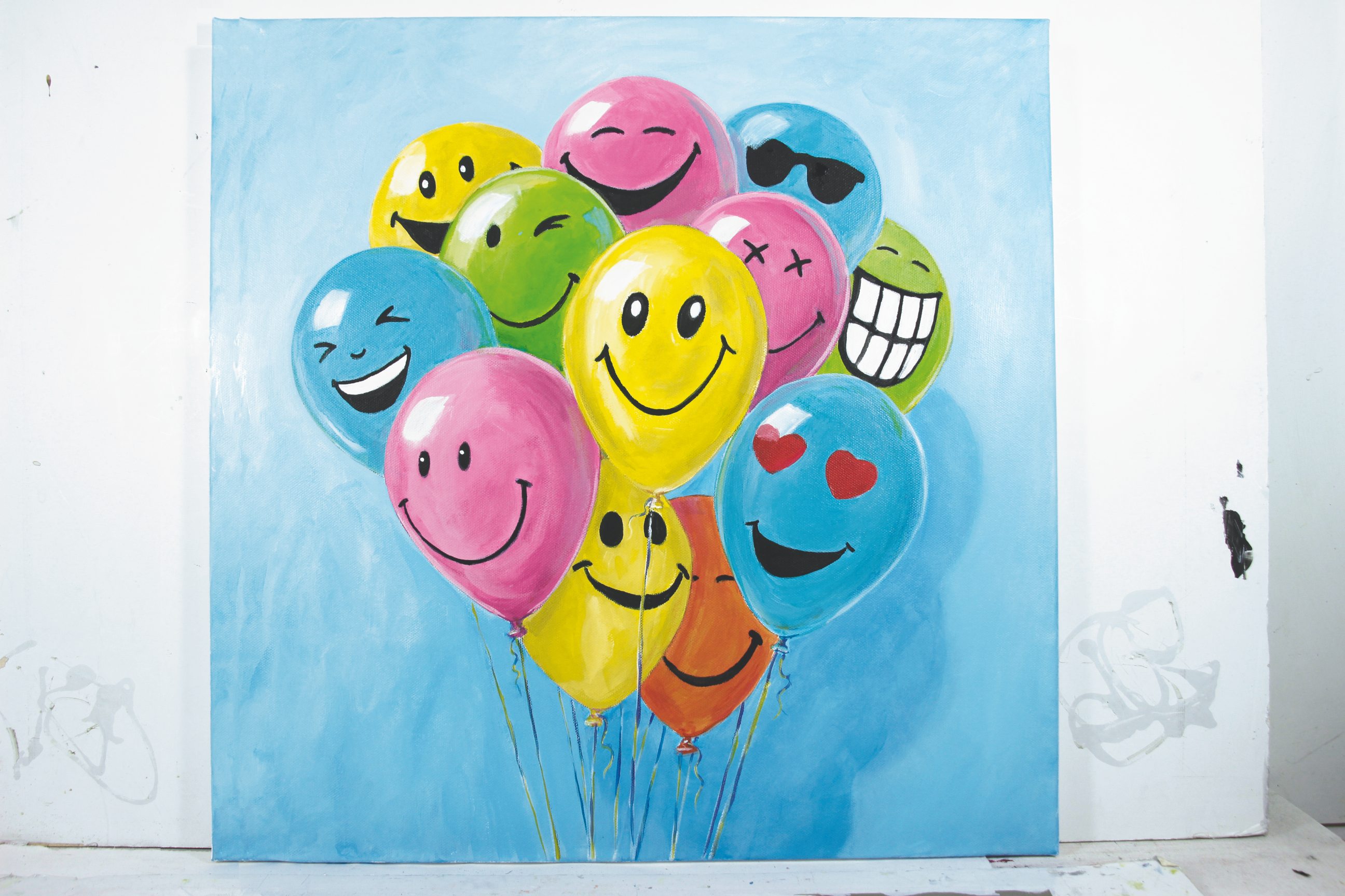 Bunte Ballons mit verschiedenen Gesichtern auf blauem Hintergrund, fröhlich und verspielte Motive, handgemalt.