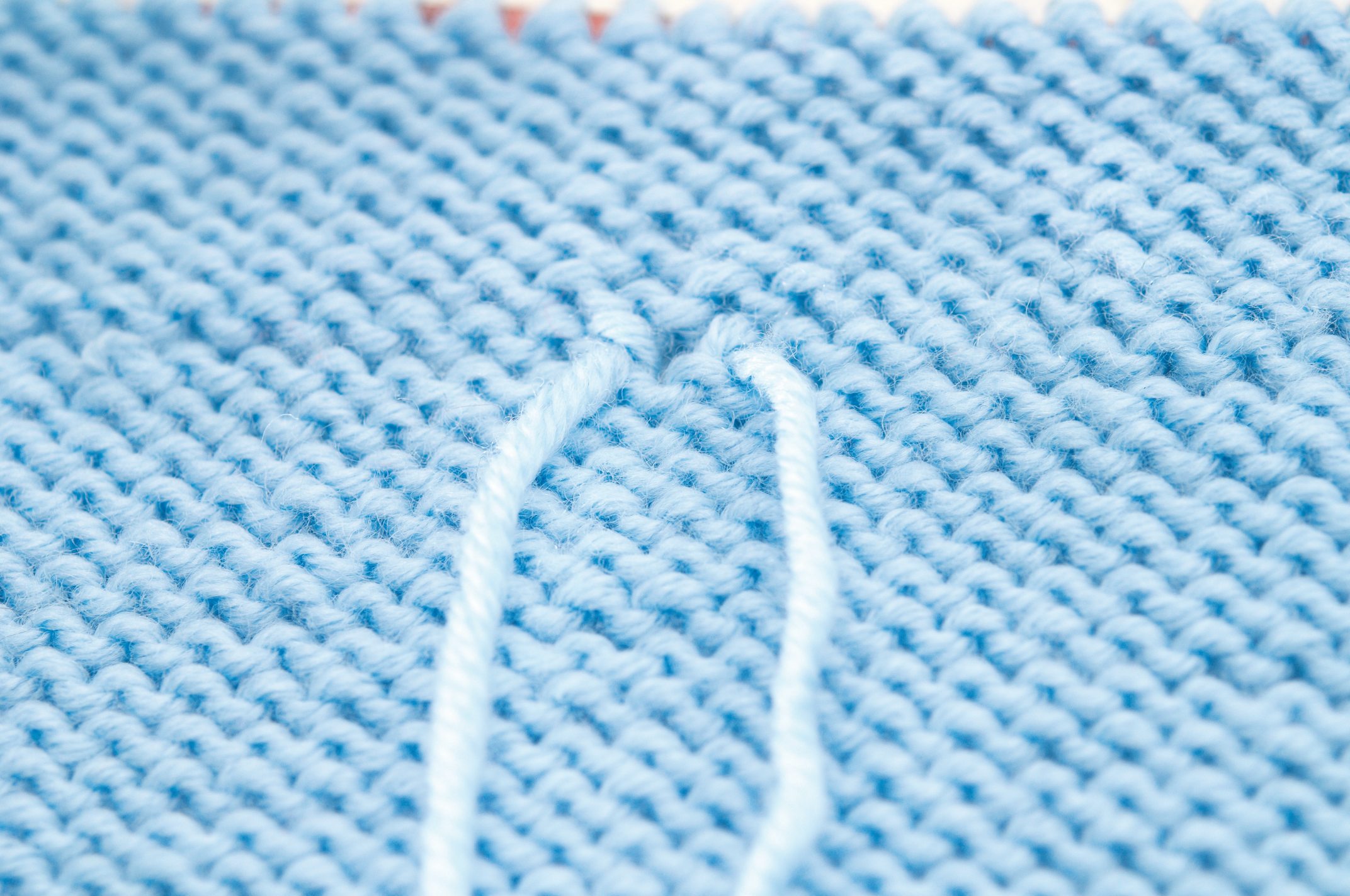 Hellblau gestricktes Material, gleichmäßige Maschen, handgemacht, detailreich, DIY-Optik, sanfte Textur.