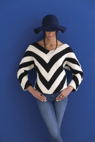 Modischer Pullover mit schwarz-weißen Streifen, V-Ausschnitt. Kombiniert mit Jeans und großem Hut.