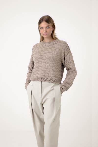 Modischer, handgemachter Strickpullover in neutralen Tönen, kombiniert mit eleganten, beigen Bundfaltenhosen.