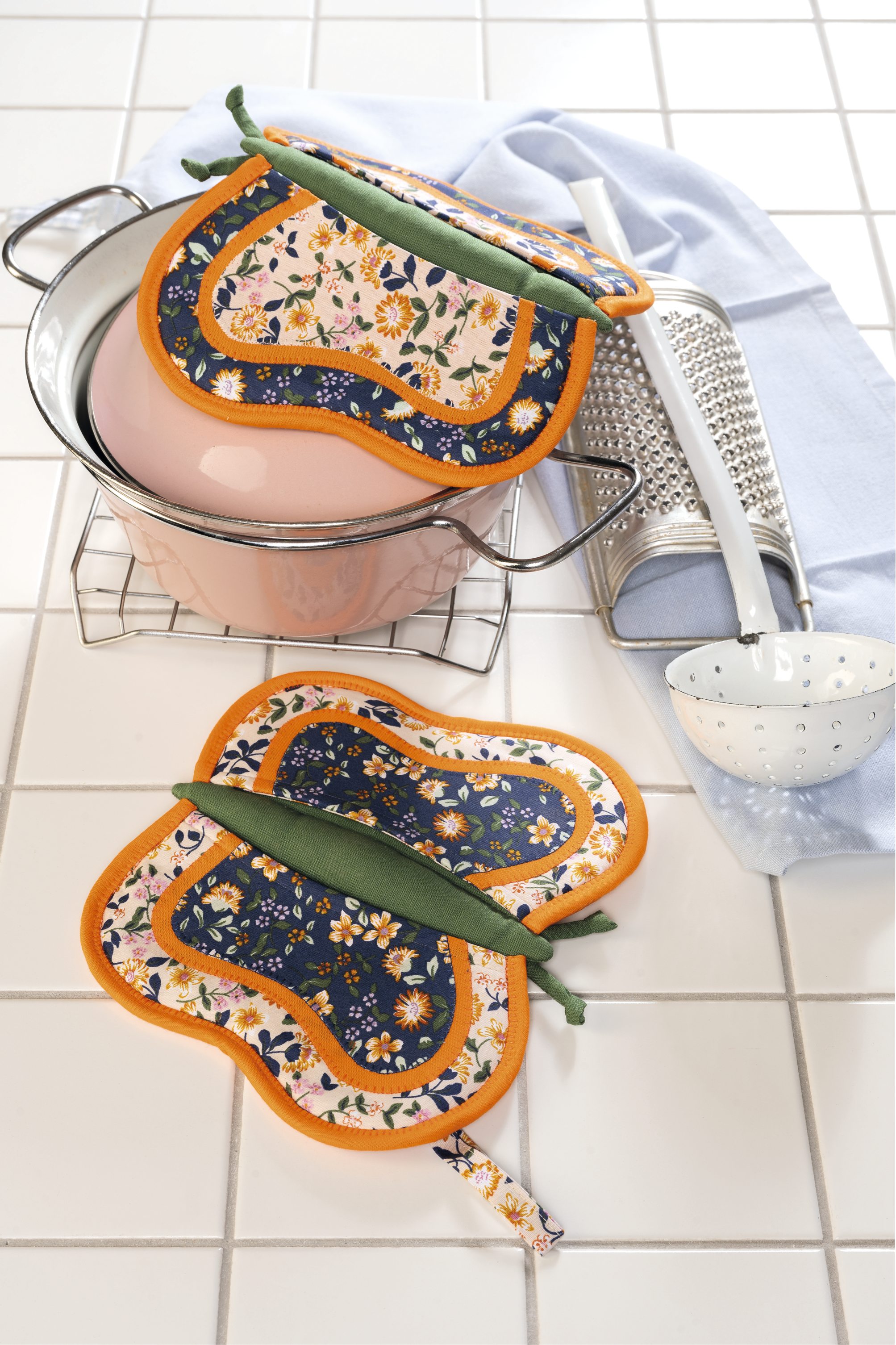 Handgemachte, blumenmusterige Topflappen, orange gerahmt, modisch und funktional, DIY-Charme.