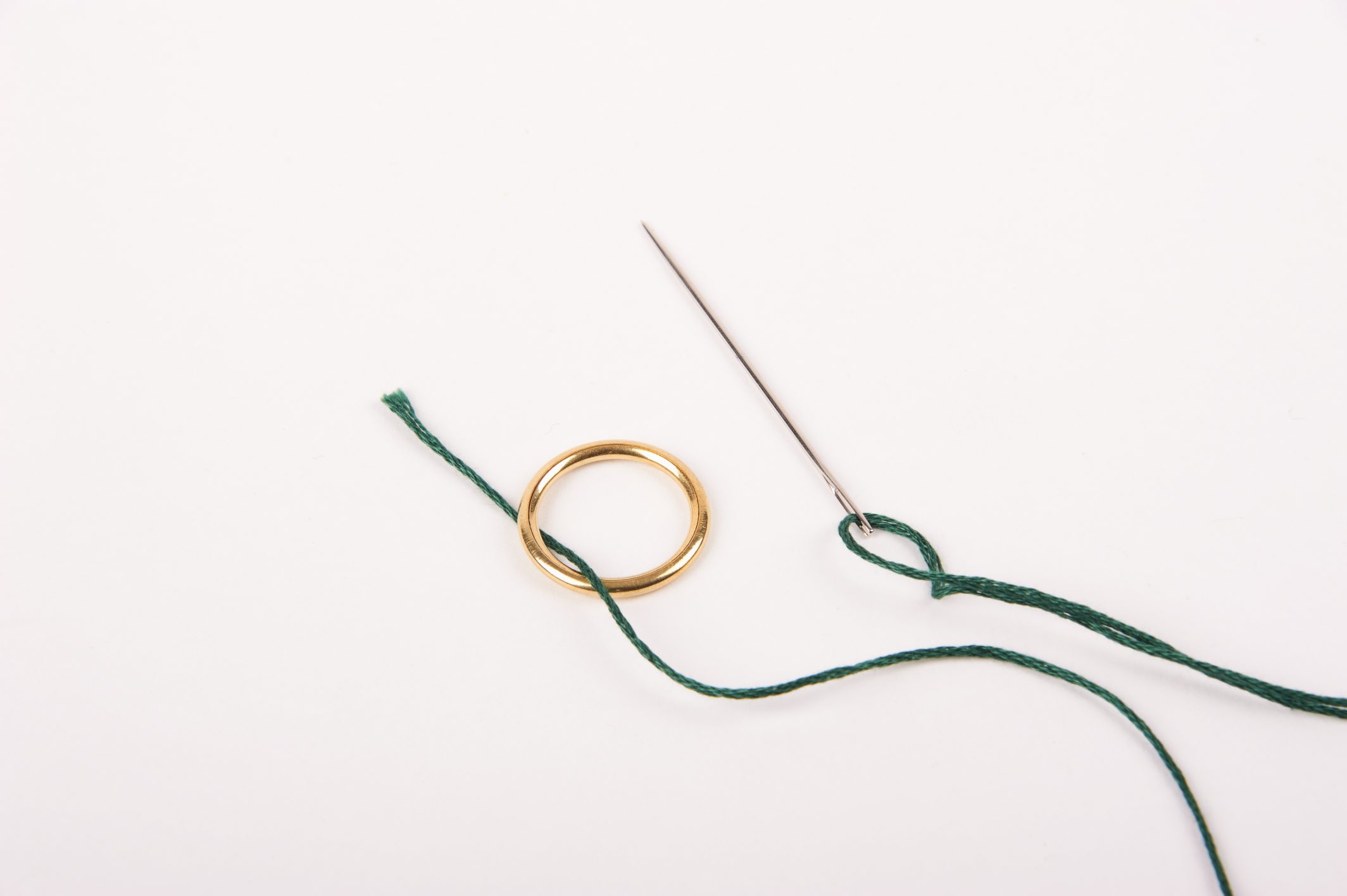 Goldring mit grünem Faden und Nadel, handgefertigt, stilvoll, einzigartig, modische DIY-Technik.
