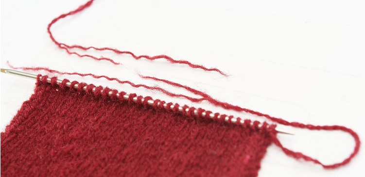 Rotes Gestricktes, feine gleichmäßige Maschen, DIY-Handarbeit; warm, gemütlich, stilvoll.