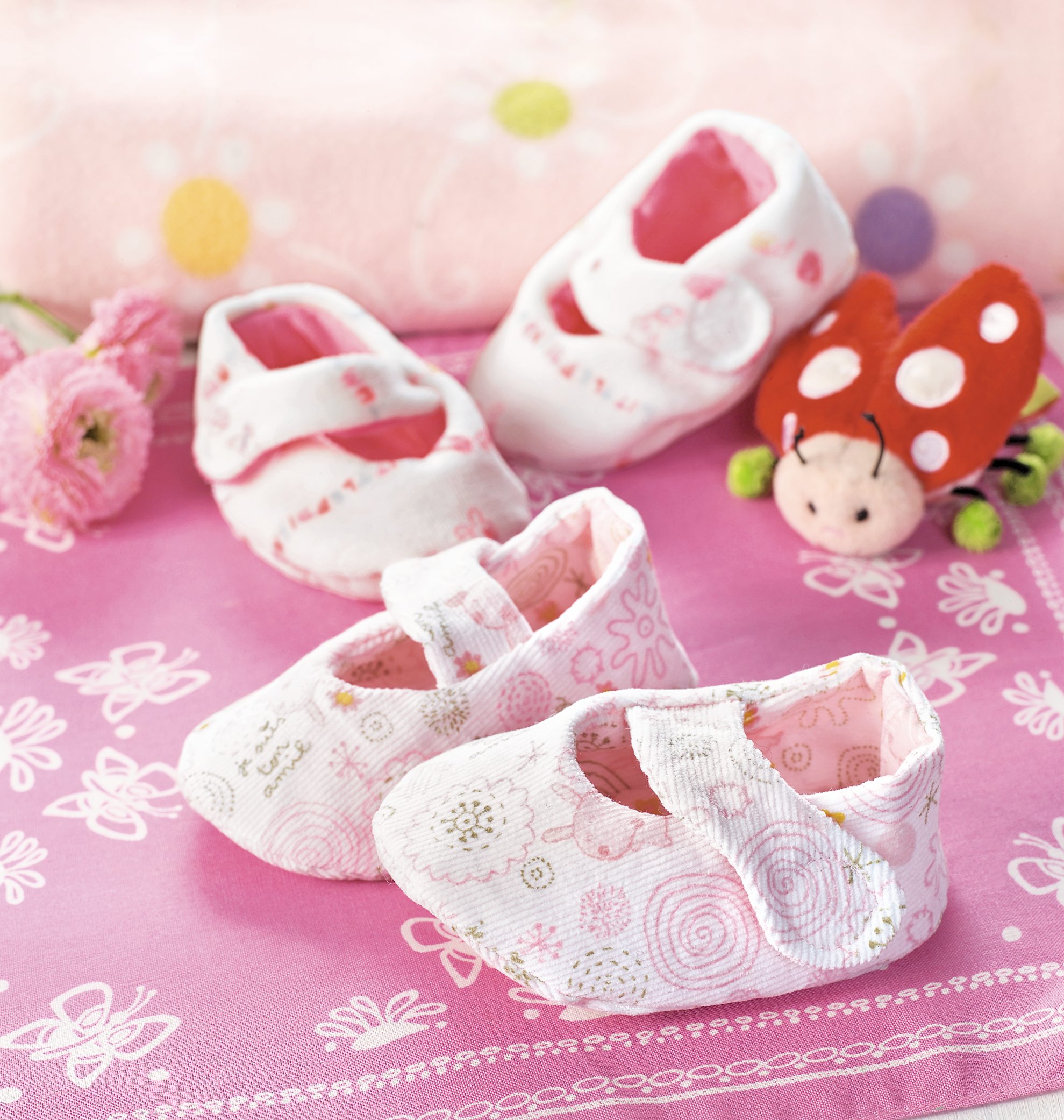 Handgemachte Babyschuhe in Rosa mit zarten Mustern, modisches Design, gepolsterter Innenstoff, ideal für Neugeborene.
