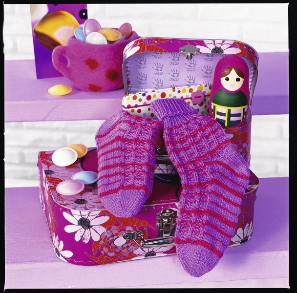 Lila handgestrickte Socken mit Streifenmuster, modisch und handgemacht, auf gemustertem Stoff.