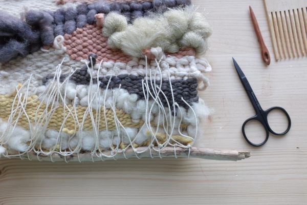 Bunte, handgewebte Textilien in Erdtönen. DIY-Handarbeit mit verschiedenen Garnstrukturen und kreativen Mustern.
